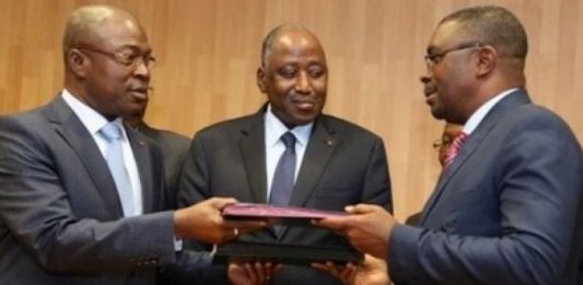 Théodore Gnagna Zadi et le ministre de la Fonction publique, sous le regard du premier ministre Amadou Gon Coulibaly, lors de la signature de l'accord de trêve